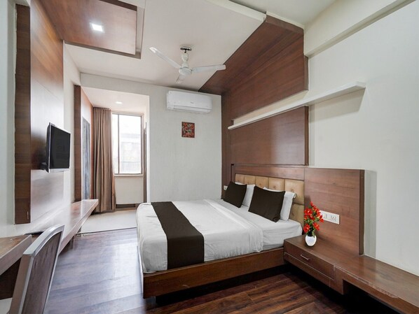 A hotel room with a bed, bedside table, TV, and a ceiling fan.