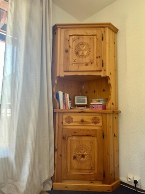 A wooden cabinet with two doors and a shelf, containing books and a small framed picture. - Appartement au pied des pistes Chez NEll (Molines-en-Queyras)