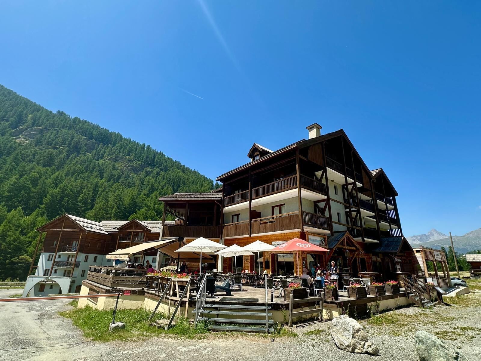 A multi-story wooden building with outdoor seating and a mountain backdrop.