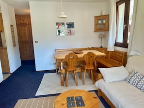A cozy living room with a wooden dining table, chairs, a sofa, and a coffee table. - Appartement au pied des pistes Chez NEll (Molines-en-Queyras)