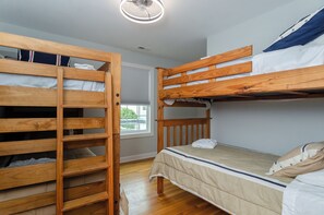A bunk bed room with a wooden ladder, a window with blinds, and a ceiling fan. - Spacious Coastal Retreat (Kure Beach)