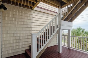A wooden staircase with white railings leading to a covered porch area. - Spacious Coastal Retreat (Kure Beach)