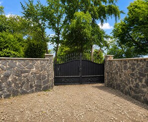 A gated entrance with a stone wall and a metal gate.