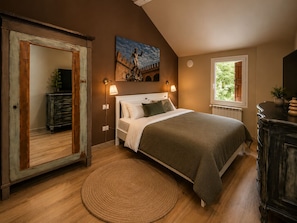 Une chambre à coucher avec un lit, des lampes de chevet, un grand miroir, un tableau, une fenêtre et une commode en bois.