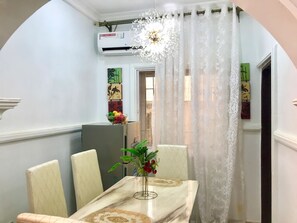 Comedor con una mesa de mármol, sillas, una lámpara de araña y una cortina decorativa.