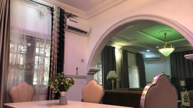 Uma sala de jantar com mesa, cadeiras e um vaso de flores.