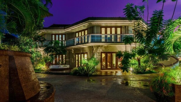 A multi-story hotel with a well-lit entrance, a covered outdoor seating area, and lush tropical landscaping. - Argo  by Trance (Sancoale)