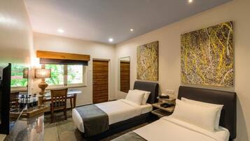 A hotel room with two beds, a desk, a chair, a TV, and artwork on the walls.