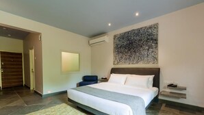 A modern hotel room with a large bed, a wall-mounted air conditioner, and a textured artwork above the bed. - Argo  by Trance (Sancoale)