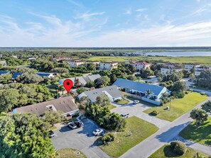 An aerial view of a residential area with houses, a parking lot, and a body of water in the distance. - Seagate Escape condo w. Beach Access (St Augustine)