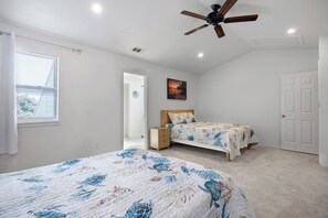 A bedroom with two beds, a ceiling fan, a door, and a window with blinds. - Seagate Escape condo w. Beach Access (St Augustine)