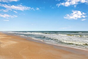 Uma praia com céu claro e ondas.