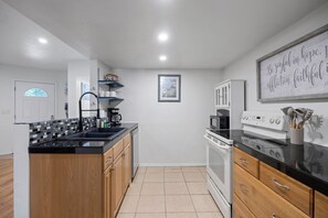 A modern kitchen with black countertops, wooden cabinets, a built-in oven, and a microwave. - Seagate Escape condo w. Beach Access (St Augustine)