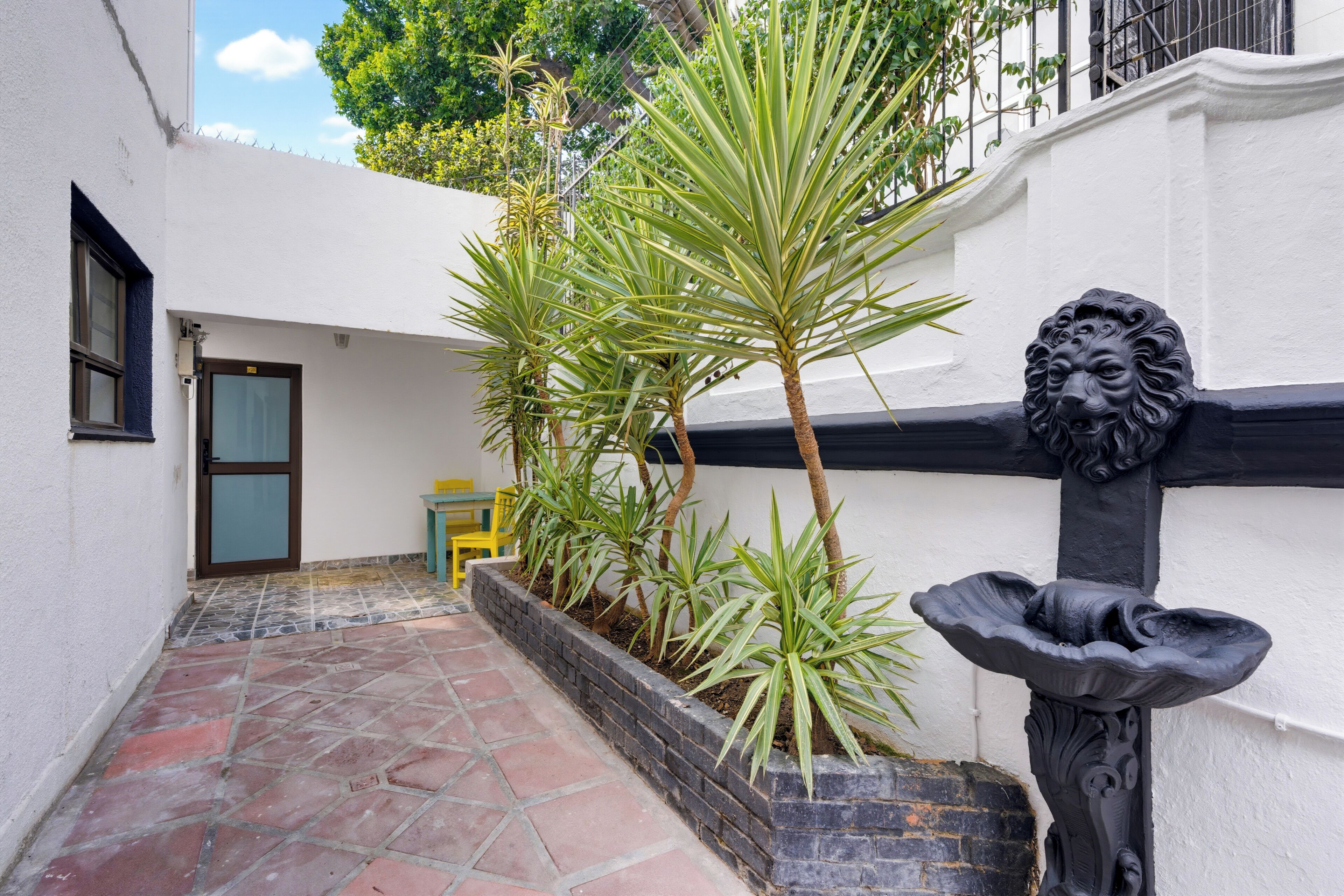 A courtyard with a tiled floor, a small table and chair, and a statue.