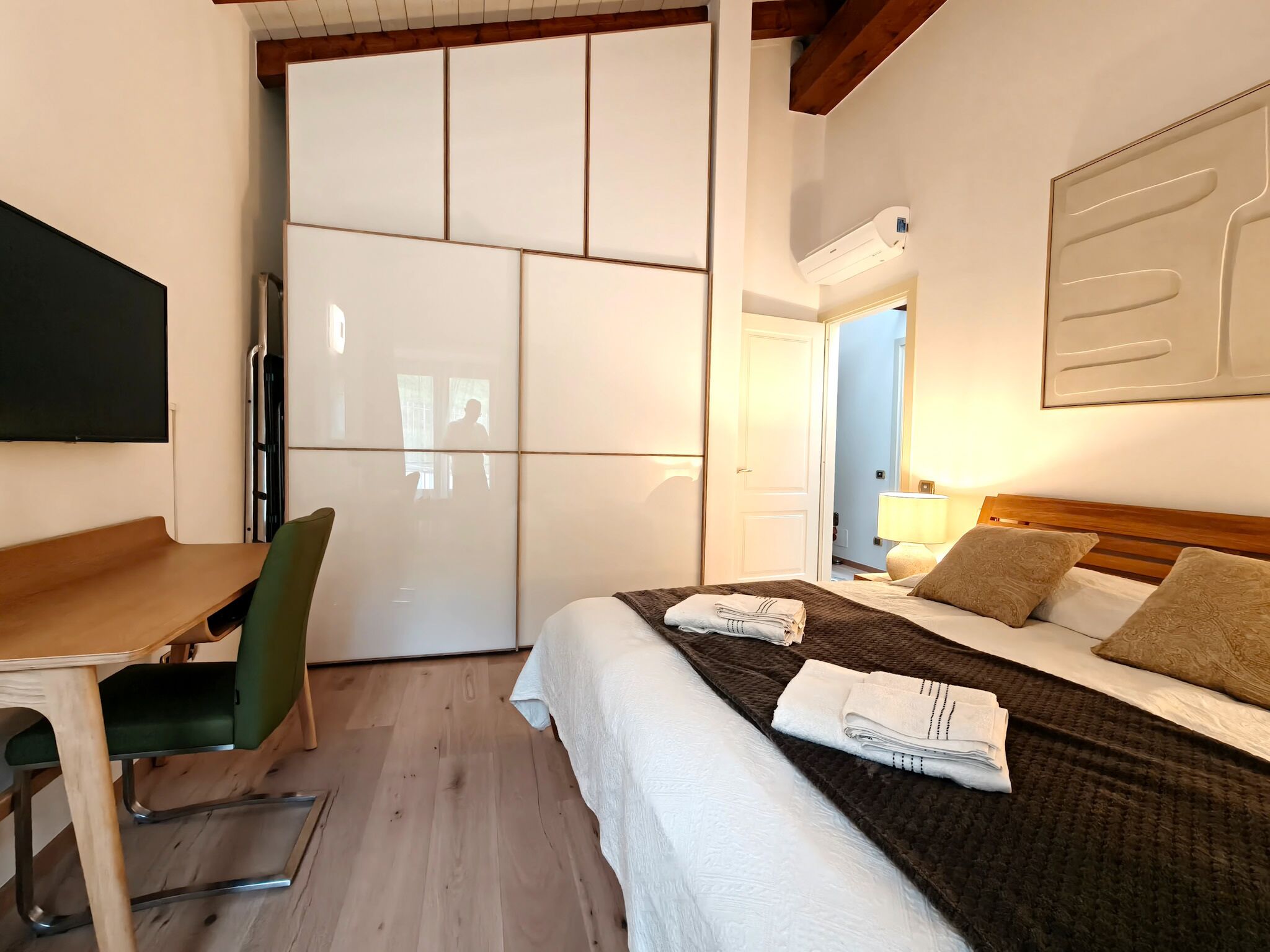 Une chambre d’hôtel avec un lit, un bureau, une chaise et une armoire.