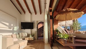 Ein großzügiger Wohnbereich mit Sofa, Fernseher und Blick ins Freie.