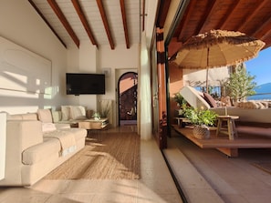 Ein großzügiger Wohnbereich mit Sofa, Fernseher und Blick ins Freie.