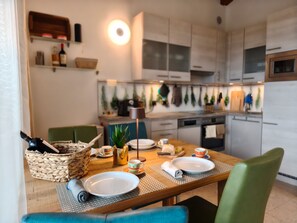 Une cuisine moderne avec des meubles blancs, une table à manger dressée avec des assiettes, des tasses et un panier.