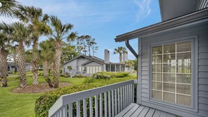 A residential property with a deck, a lawn, and palm trees. - Greenside Getaway - 2BR condo w/ pool access & golf views (Ponte Vedra Beach)
