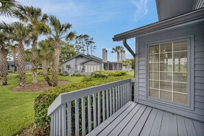 A residential property with a deck, a lawn, and palm trees. - Greenside Getaway - 2BR condo w/ pool access & golf views (Ponte Vedra Beach)