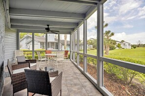A covered patio with wicker furniture, a ceiling fan, and a view of a well-maintained lawn and houses. - Greenside Getaway - 2BR condo w/ pool access & golf views (Ponte Vedra Beach)