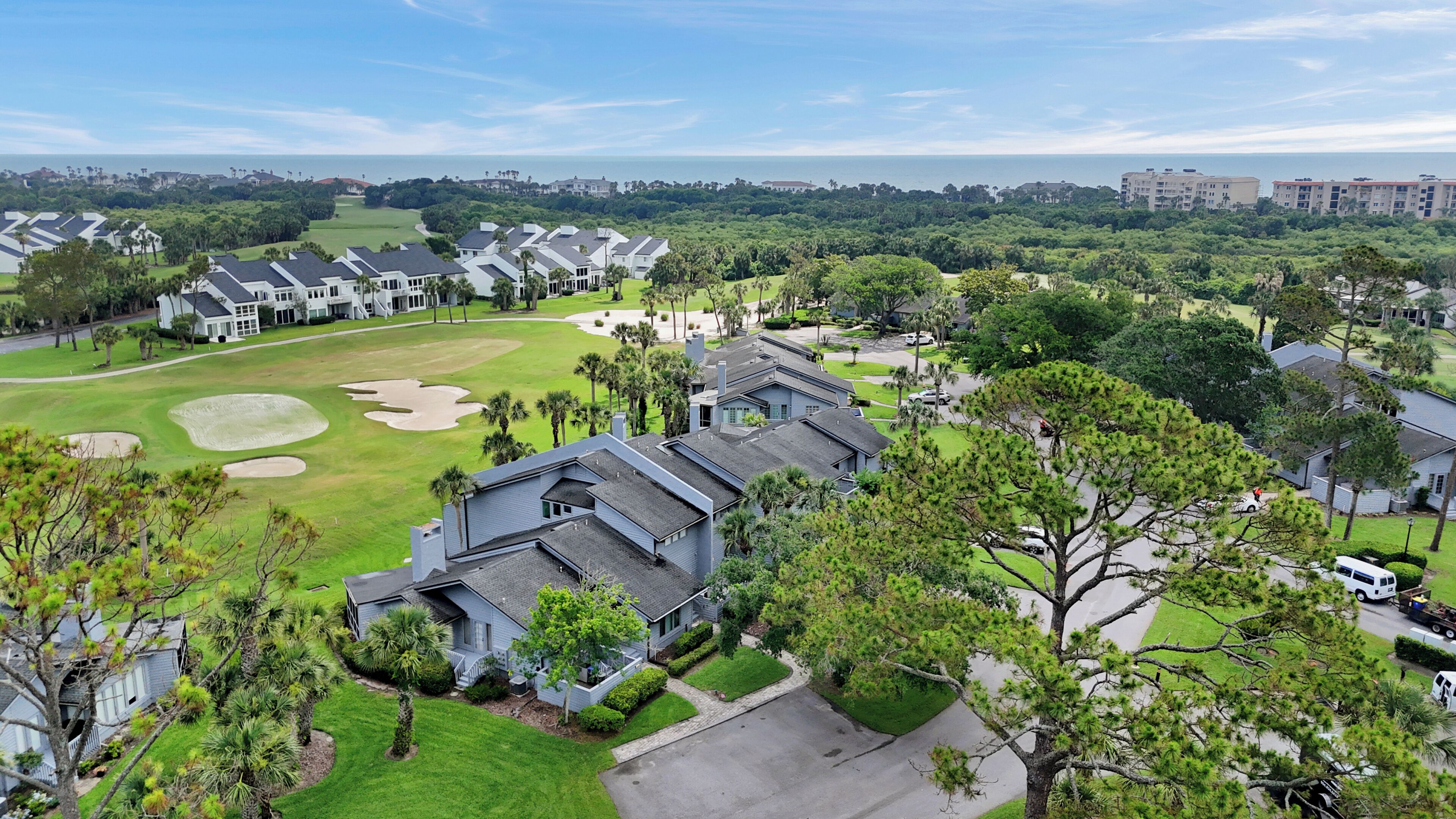 A residential area with houses, a golf course, and a view of the ocean.