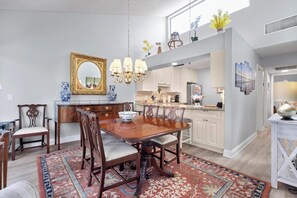 Un coin repas avec une table et des chaises en bois, un lustre et un tapis à motifs.