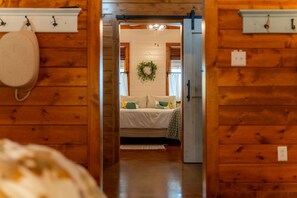 Een houten interieur met een bed, een hangende tas en een lamp.