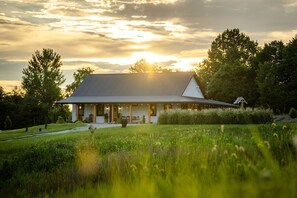 Ein Haus mit einer großen Veranda, umgeben von einem gepflegten Rasen und Bäumen.