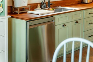 A kitchen with a stainless steel dishwasher, light green cabinets, and a wooden countertop. - The Farmhouse on Barton | Hocking Hills, Hot Tub (Logan)