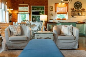 A cozy living room with two armchairs, a coffee table, and a lamp. - The Farmhouse on Barton | Hocking Hills, Hot Tub (Logan)