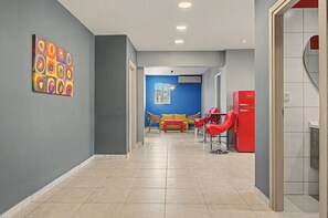 Ein Flur mit blauer Wand, einem roten Kühlschrank und einem gelben Sofa.