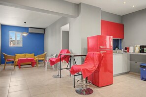 Un espacio habitable compacto con kitchenette, una zona de comedor con mesa y sillas, y un sofá.