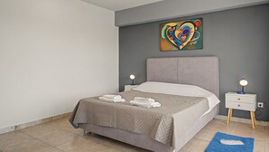 Quarto moderno com cama, duas mesas de cabeceira com luminárias, uma obra de arte na parede e um tapete azul.