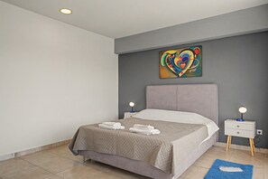 Ein modernes Schlafzimmer mit einem Bett, zwei Nachttischen mit Lampen, einem Wandbild und einem blauen Teppich.