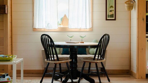 A dining area with a round table, two chairs, and a window with curtains. - The Cottage Barn on Barton | Hocking, Cozy Retreat (Logan)