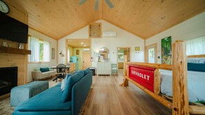 A cozy cabin interior with a living area, a kitchen, and a sleeping area. - The Cottage Barn on Barton | Hocking, Cozy Retreat (Logan)