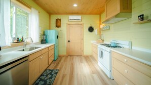A compact kitchen with wooden cabinets, a sink, a stove, and a refrigerator. - The Cottage Barn on Barton | Hocking, Cozy Retreat (Logan)