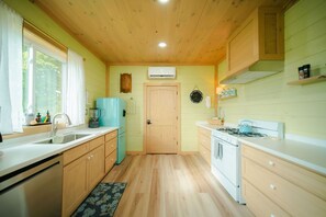Eine kleine Küche mit Holzausstattung, einer Spüle, einem Herd und einem Kühlschrank.