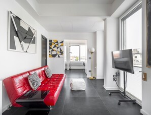 Ein modernes Wohnzimmer mit einem roten Ledersofa, einem Flachbildfernseher und Kunstwerken an den Wänden.