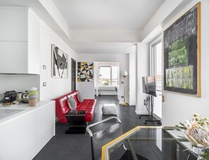 A modern living room with a red sofa, a glass coffee table, and a large abstract painting on the wall. - Porta Nuova 52 Design Apartment R&R (Milan)