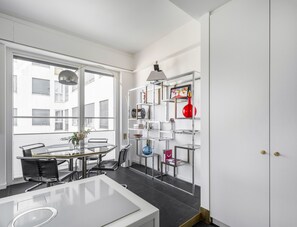 A modern kitchen with a dining area, large windows, and a metal shelving unit with various items. - Porta Nuova 52 Design Apartment R&R (Milan)