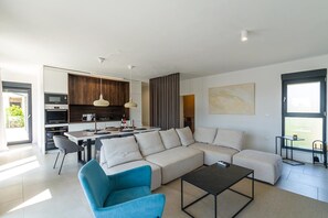 A modern living room with a sofa, a coffee table, and a blue armchair. - Enjoy a relaxing stay at Villa Sea View Saleda, a modern four-bedroom villa for up to nine guests with a private pool, jacuzzi, summer kitchen and panoramic views towards the sea. (Krnica)