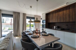 Uma cozinha moderna com armários de madeira escura, uma ilha central com bancadas e iluminação pendente.