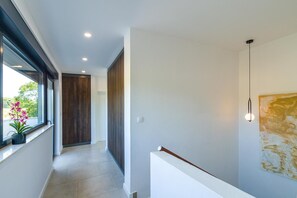 A modern hallway with a potted plant, a wooden door, and a wall-mounted light fixture. - Enjoy a relaxing stay at Villa Sea View Saleda, a modern four-bedroom villa for up to nine guests with a private pool, jacuzzi, summer kitchen and panoramic views towards the sea. (Krnica)