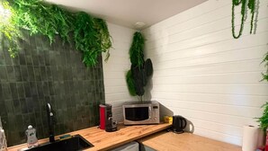 A compact kitchen with a wooden countertop, a built-in dishwasher, a microwave, and a sink. - L'Évidence - Love Room & Spa (Chaveignes)