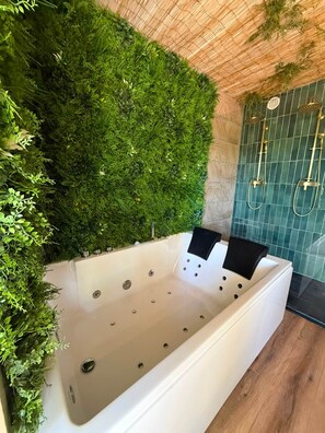 Un baño moderno con una bañera grande, una pared verde y una zona de ducha.