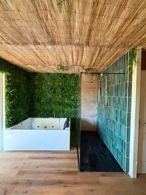 Um banheiro moderno com uma banheira grande, área de chuveiro e uma parede verde.