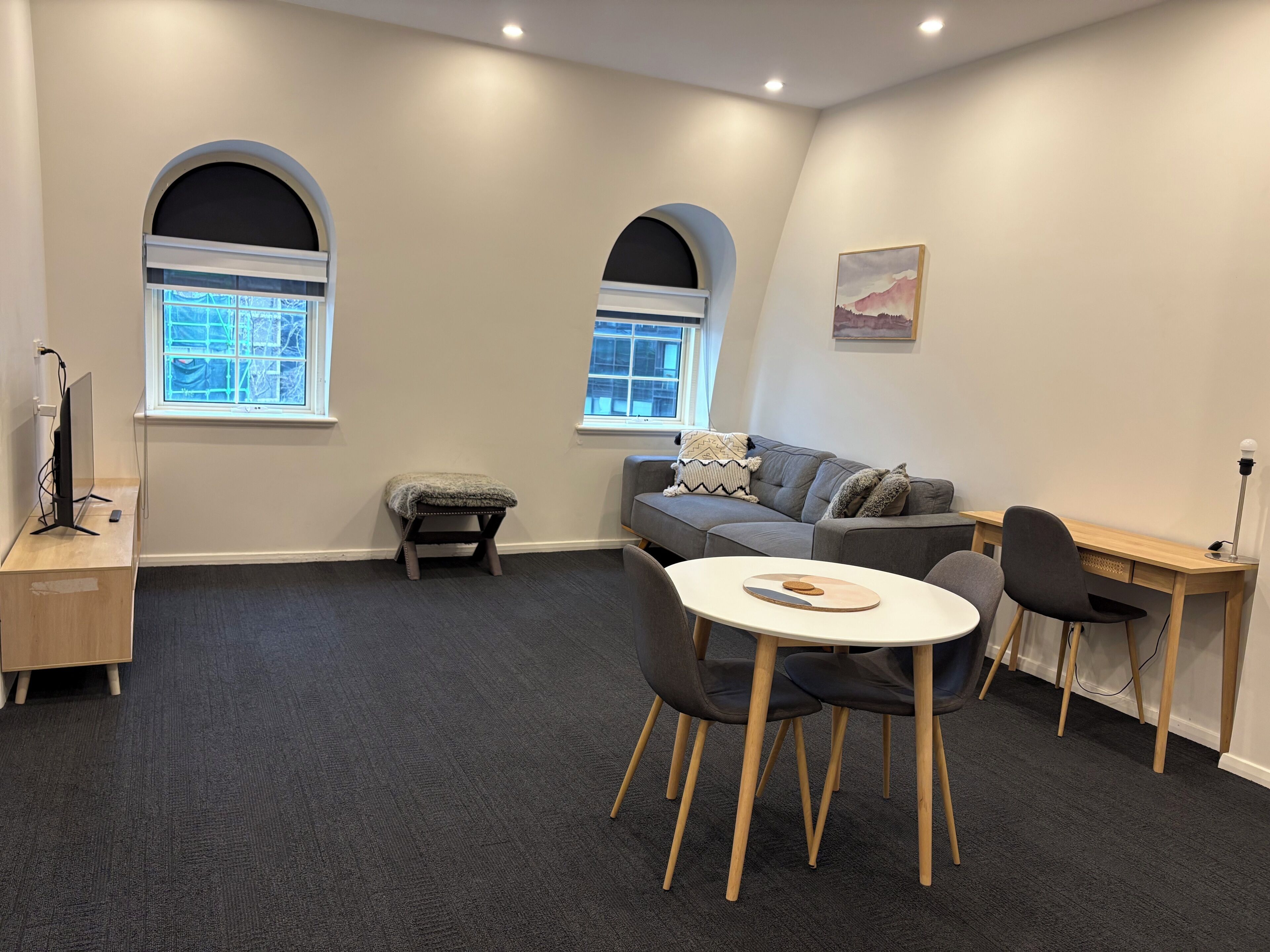A modern living room with a grey sofa, a small table, and a desk area.