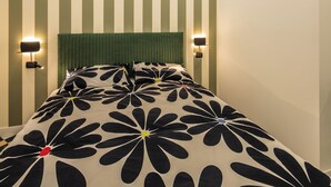 Ett hotellrum med en säng, randiga väggar och taklampor.